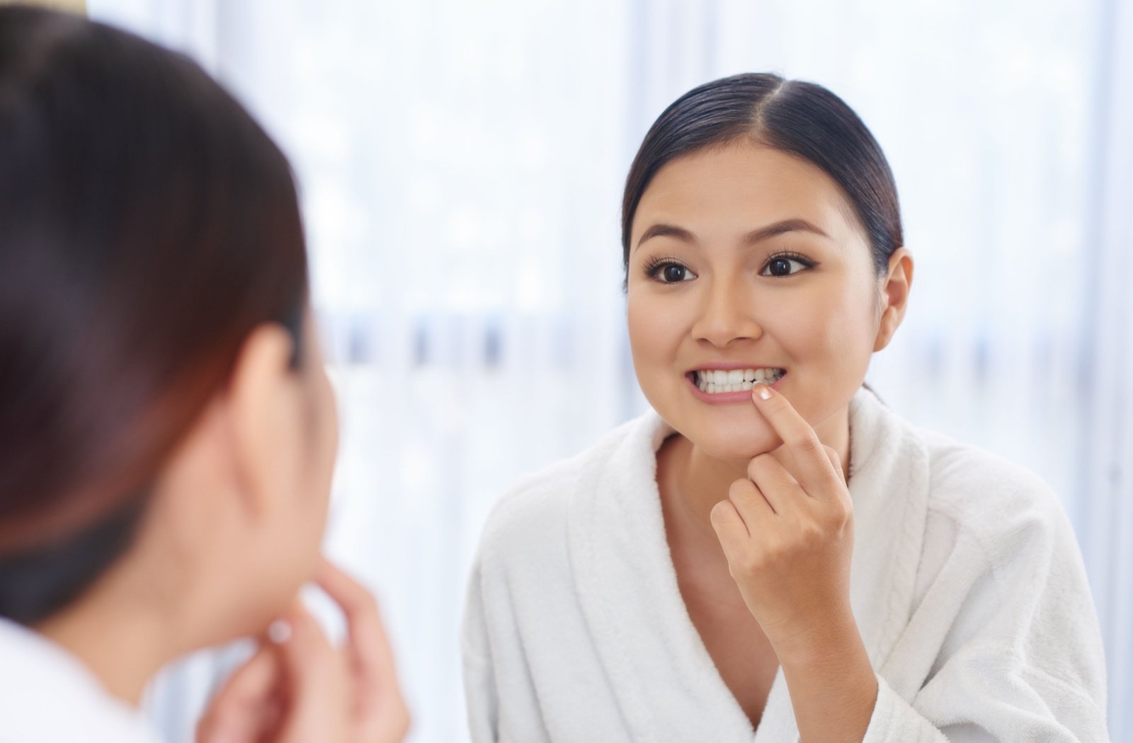 A young woman looking at her teeth in the mirror